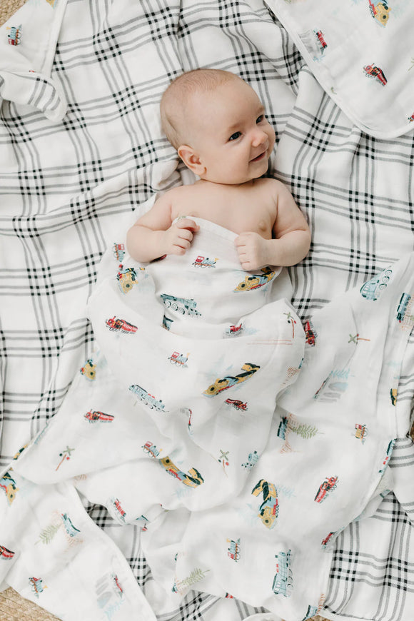 A baby in the all aboard muslin swaddle