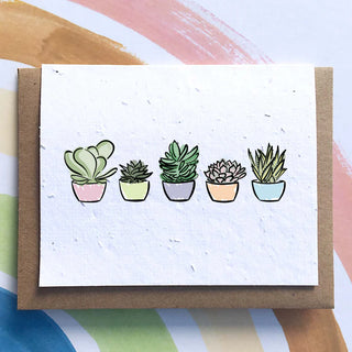 A white card on top of a brown envelope. On the card there are 5 illustrated succulents in pink, yellow, purple, orange and blue pots.