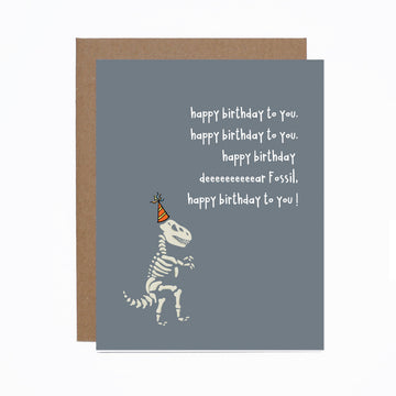 Birthday Fossil Card - Handmade Canadian birthday card with a playful dinosaur fossil wearing a party hat on gray background, unique gift design.
