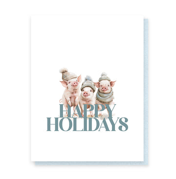 Happy Holidays Pigs Card - White Christmas card featuring three pigs wearing winter hats and scarves with "Happy Holidays" text, unique handmade.