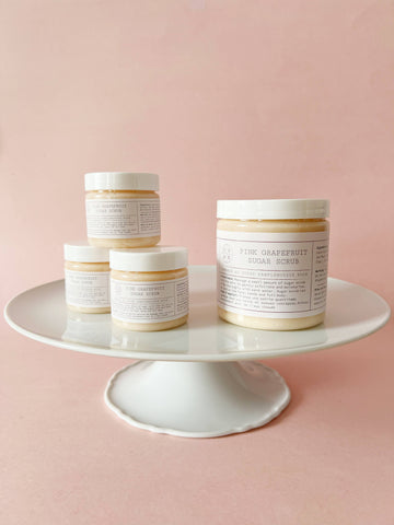 Pink Grapefruit Sugar Scrub - Set of four Pink Grapefruit Sugar Scrub jars with white lids on white pedestal, handmade Canadian spa gift.