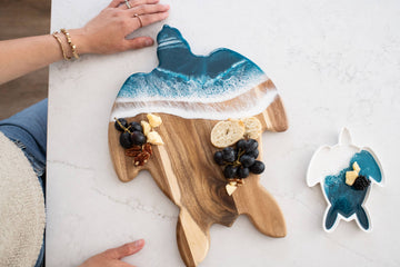 Resin Turtle Cheese / Charcuterie Board - Handmade resin and wood turtle-shaped cheese board with ocean wave design, holding crackers and grapes.