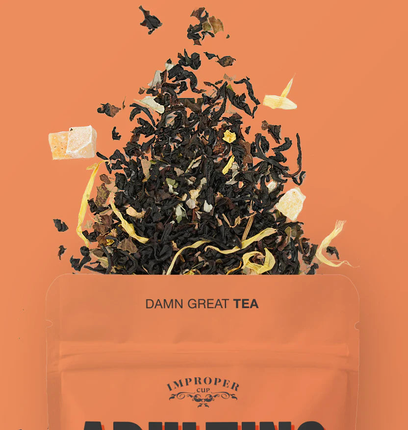 The top quarter of the bag is visible and a blend of tea leaves spills out of the top.