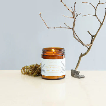 Amber & Driftwood Soy Candle - Amber glass jar soy candle with minimalist white label featuring delicate botanical illustration.