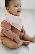 A baby wearing the plain pink bandana bib from the baby dinomite set