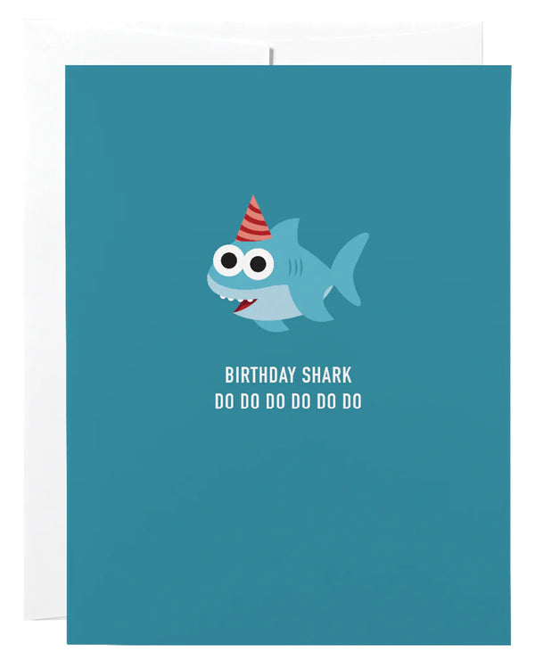 A blue card with a shark wearing a party hat with the words 