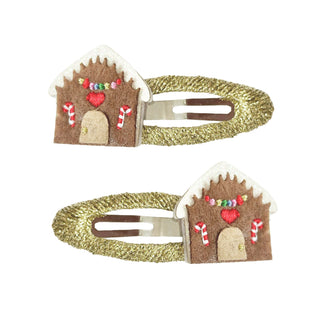 2 gold hair clips with gingerbread houses on them