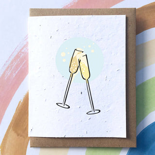 A white card with a brown envelope. On the card there are two illustrated champagne glasses together in a bubble