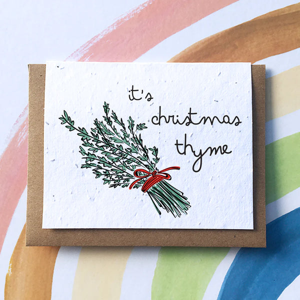 A white card with a bundle of thyme tied together by a red ribbon along with the words “It’s Christmas Thyme”
