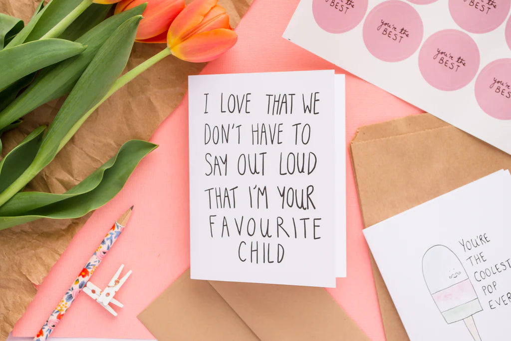 A white card with the words "I love that we don't have to say out loud that I'm your favourite child"