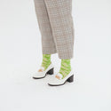 A close up of a model wearing the socks with white loafers