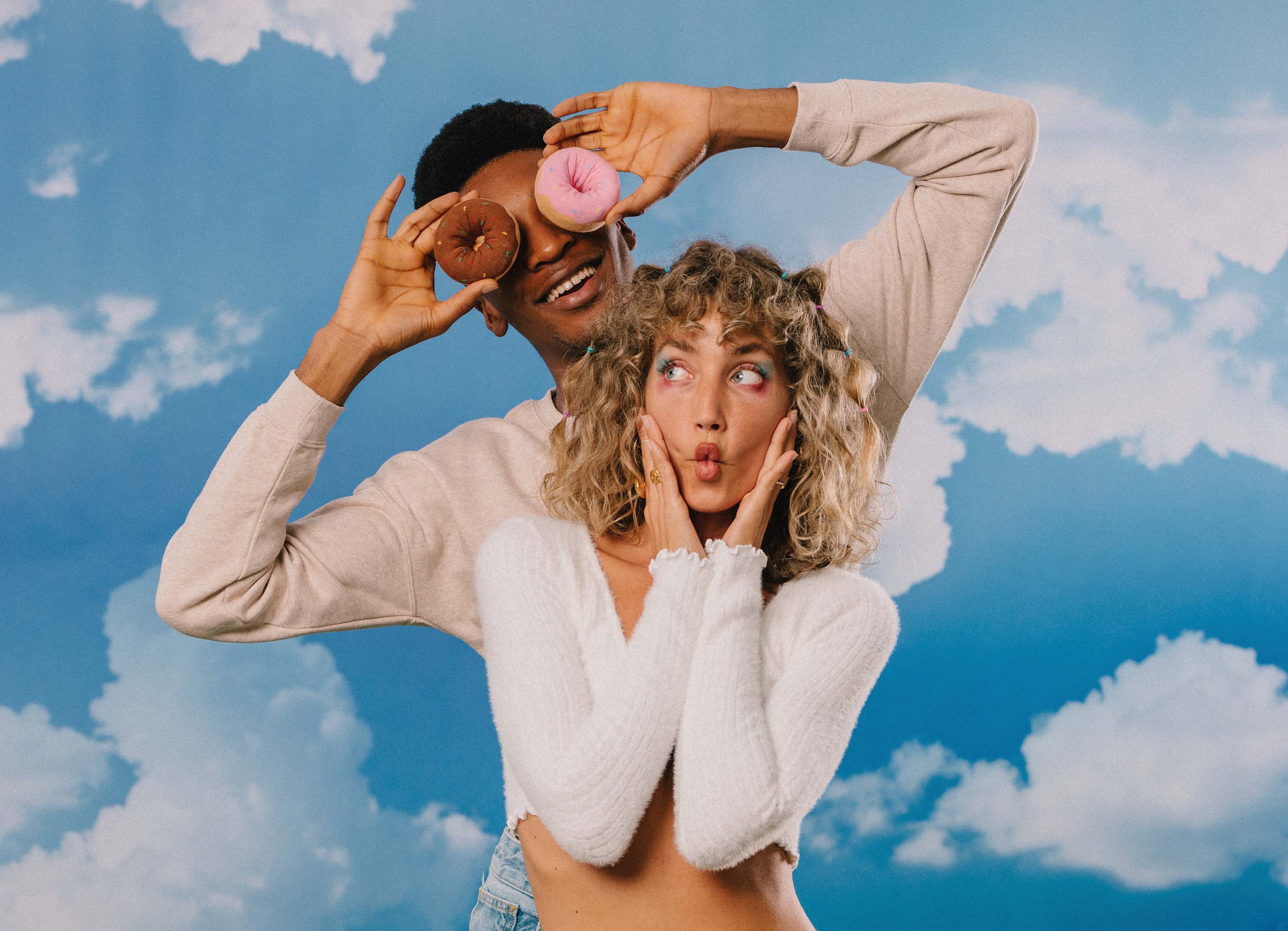 A model behind another model holding the socks shaped like a donut over his eyes.