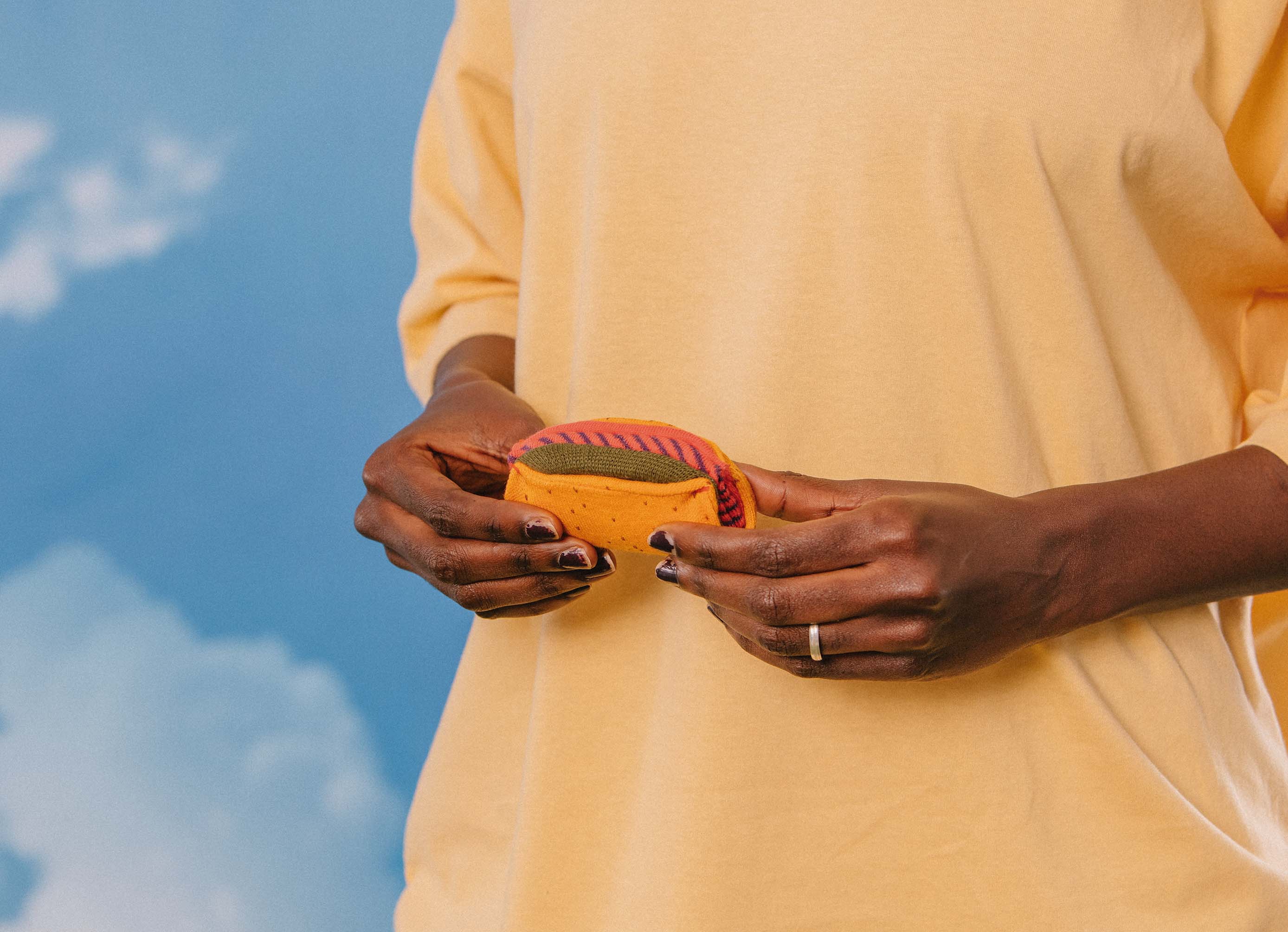 A close up of a model with black nail polish holding the taco near their waist