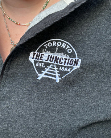 The Junction Toronto 1/4 Zip Sweater | Campus Crew - Dark charcoal quarter-zip sweater with white embroidered Toronto Junction logo on chest, soft knit fabric.