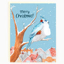 A sky blue card with a blue jay wearing earmuffs and holding a red gift sits on a barren tree branch above houses.