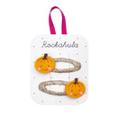 Little Pumpkin Bag - Set of two glittery gold hair clips with smiling orange pumpkin decorations on white card labeled Rockahula.