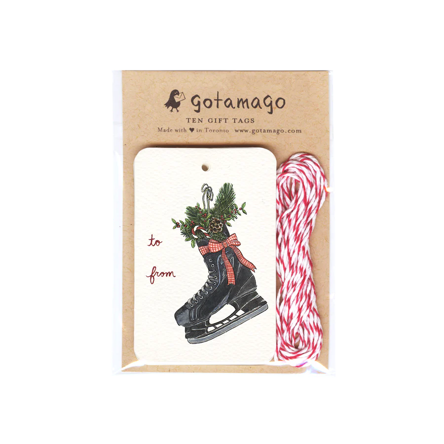 A white gift tag with a black skate filled with holly, a pinecone and a candy cane next to red font reading "to" and "from". Next to the tags are red and white twine.