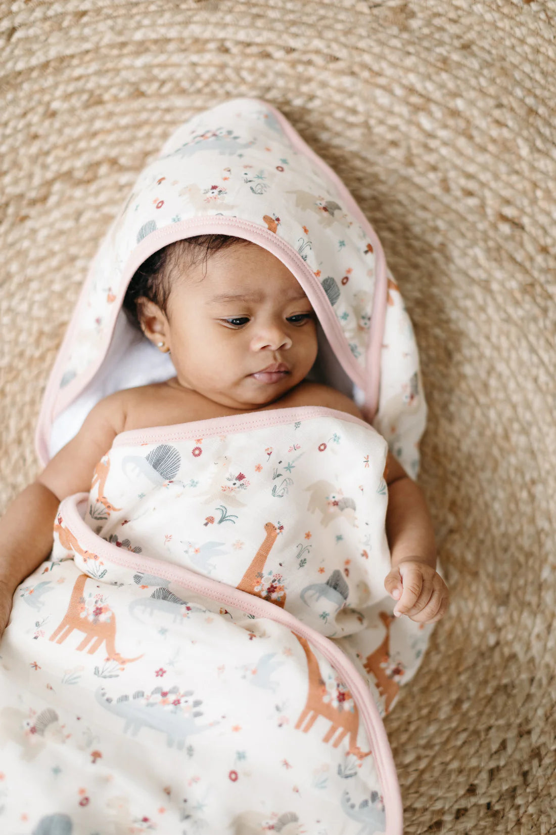 A baby wearing the baby dinomite hooded towel (dinosaurs with flowers)