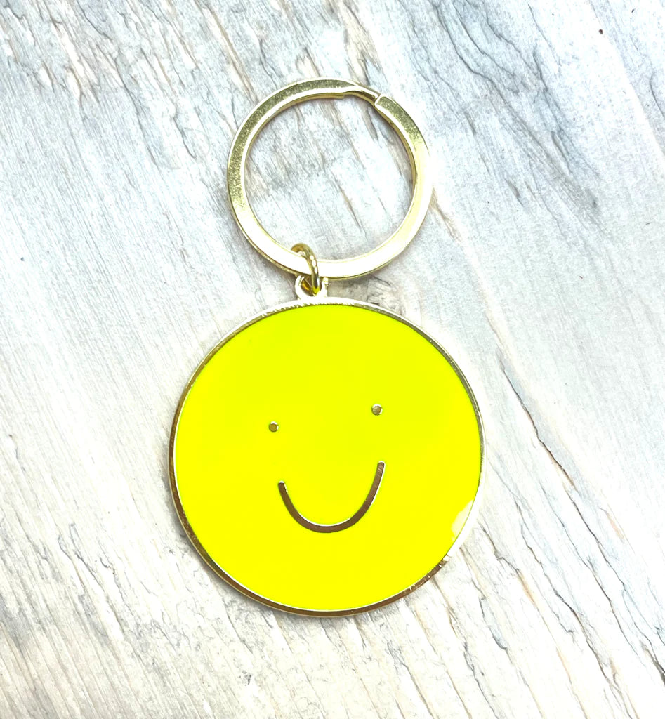 A keychain of a yellow circle with a smiley face in the middle