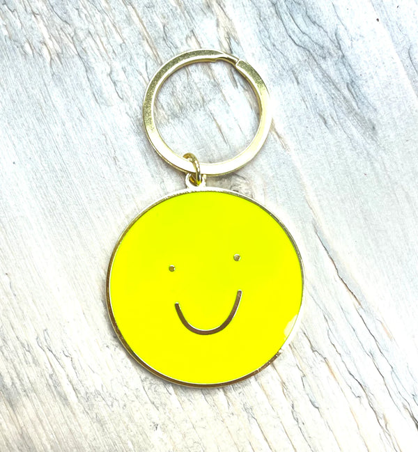A keychain of a yellow circle with a smiley face in the middle