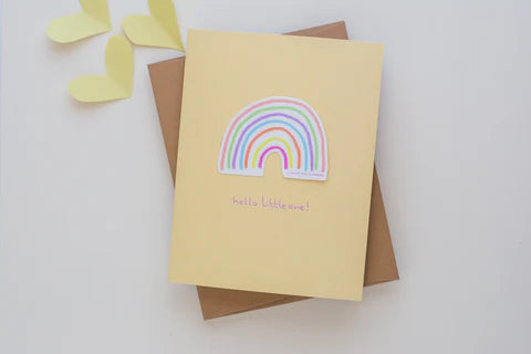 Pastel orange card with a vinyl sticker of a rainbow and the words "Hello little one!"