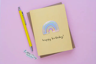 A beige colored card with a removable rainbow sticker in the middle and the words 