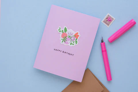 A pink card with a vinyl sticker of a bouquet of flowers and the words 