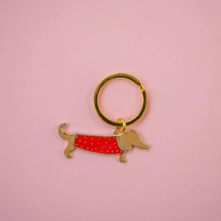 A keychain of a dachshund dog wearing a red spotted sweater