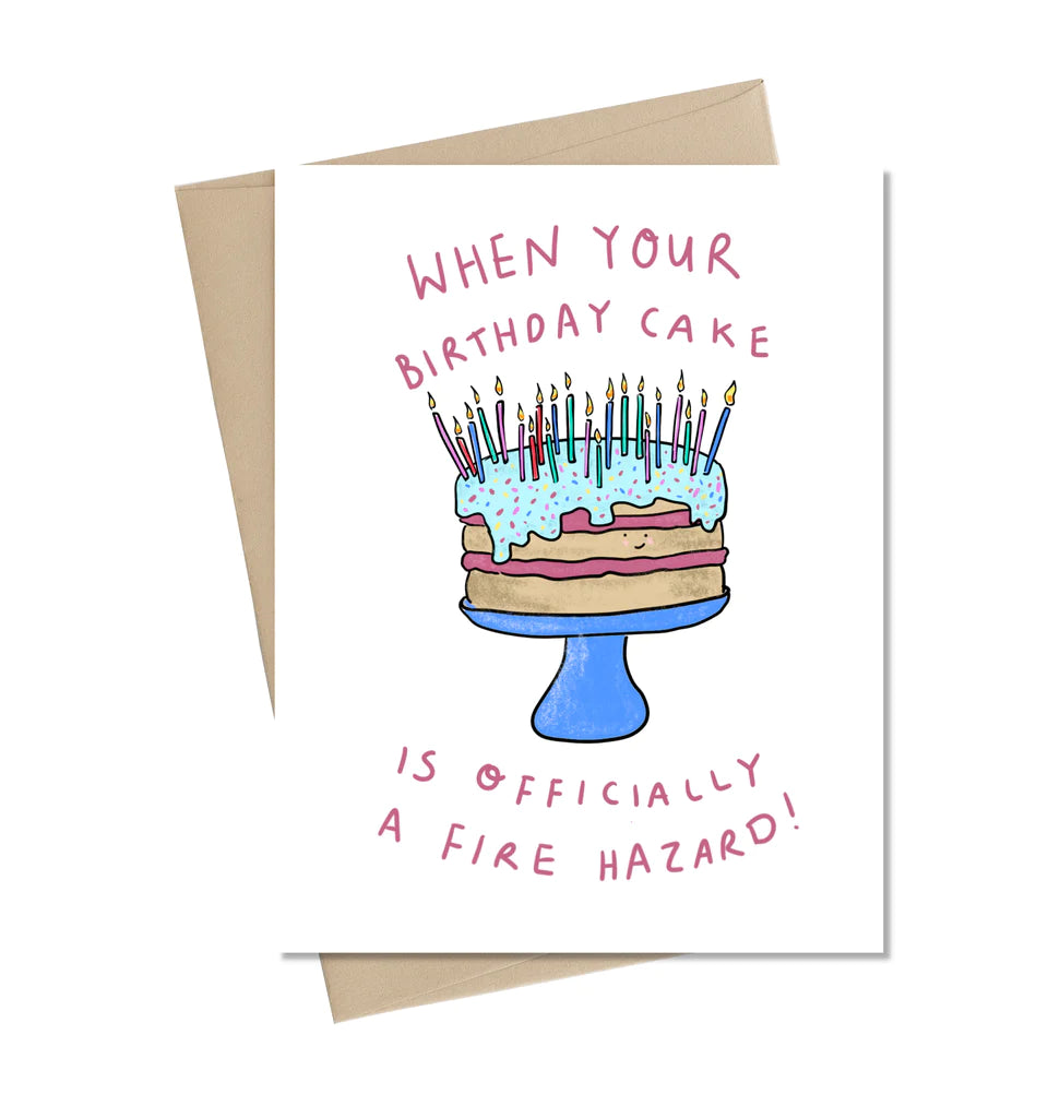 A white card with an illustrated blue and pink cake overflowing with candles. In pink reads "When your birthday cake is officially a fire hazard"