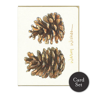 A white, horizontal card with 2 pinecones next to each other. Underneath reads in gold text 