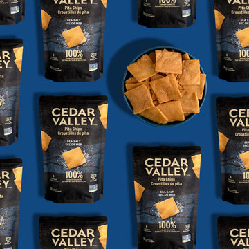Cedar Valley Pita Chips - Black and gold packages of Canadian Cedar Valley Pita Chips with a bowl of handmade, square pita chips, a unique gourmet.
