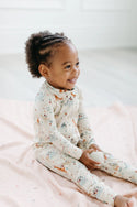 A little girl wearing the Baby Dinomite Sleeper by LouLou Lollipop