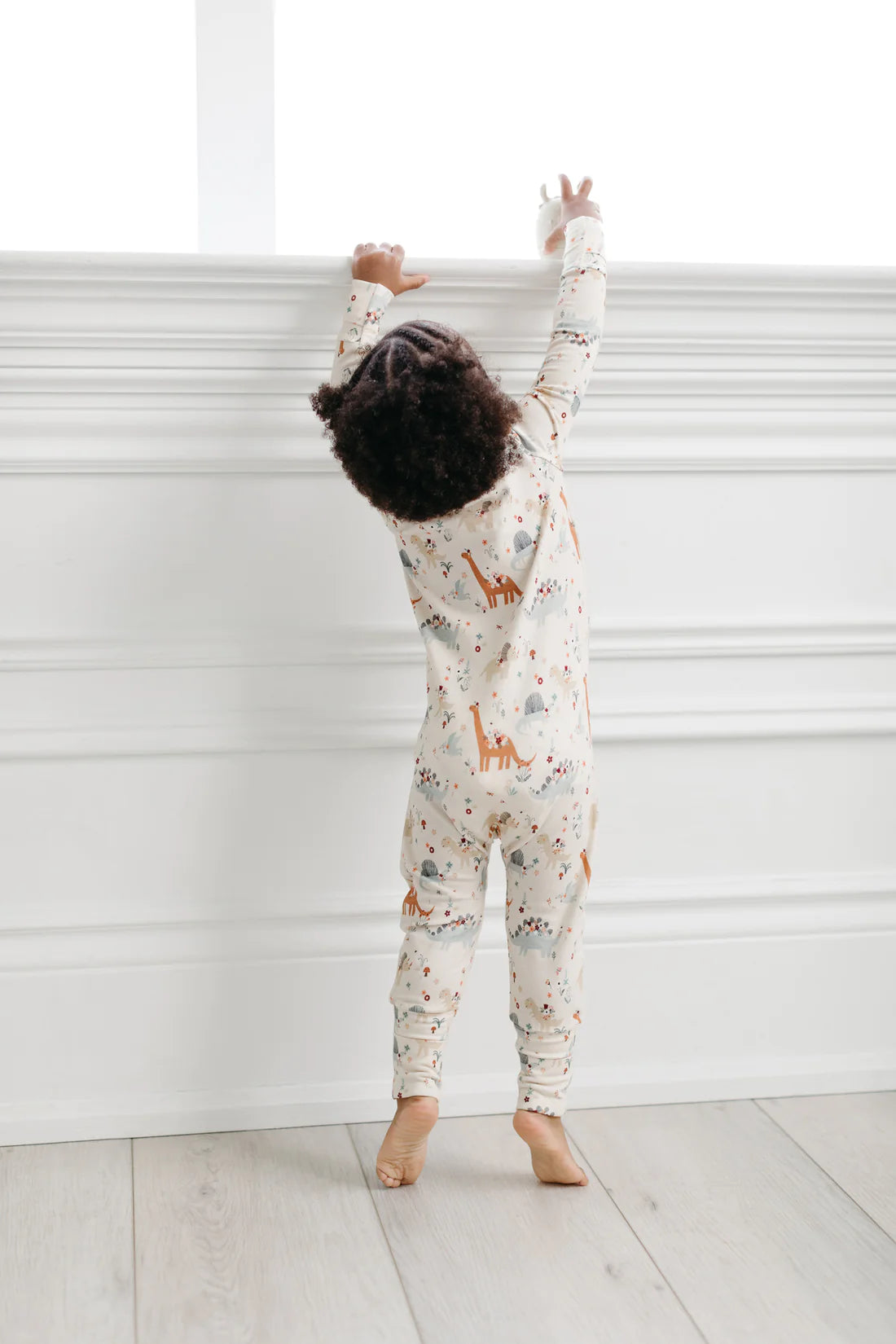  A little girl wearing the Baby Dinomite Sleeper by LouLou Lollipop