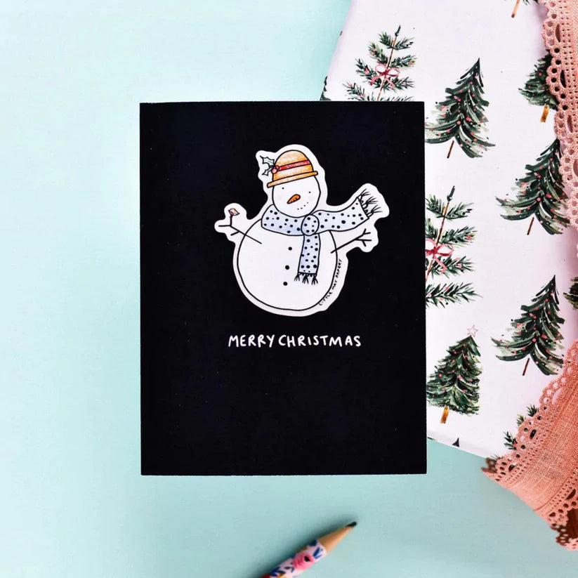 A black card with a white snowman in the center wearing a scarf and hat. Underneath reads "MERRY CHRISTMAS" in white