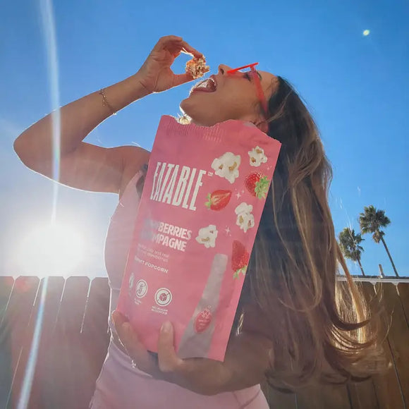 Strawberries & Champagne - Gourmet Popcorn - Handmade Canadian Strawberries & Champagne gourmet popcorn gift bag held by woman outdoors.