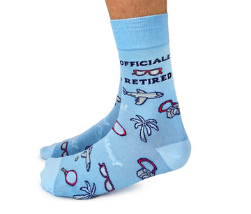 Men's Officially Retired Socks - Light blue men's socks with "Officially Retired" text, airplane, palm tree, and sunglasses motifs, handmade Canadian gift.