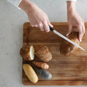 A person cutting potatoes on a cutting board