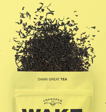 Wake the Fuck Up Tea - Yellow resealable pouch labeled "Damn Great Tea" with loose black tea leaves spilling out.