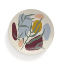 A cream coloured plate with abstract splashes of maroon, salmon, mustard yellow and light blue with green leaves painted on top