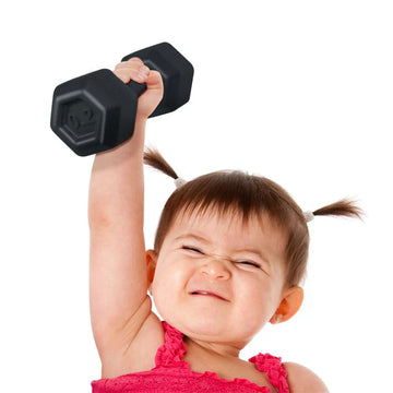 Buff Baby Dumbbell Rattle - Handheld black hex dumbbell rattle held by baby in pink outfit, unique handmade Canadian gift toy.