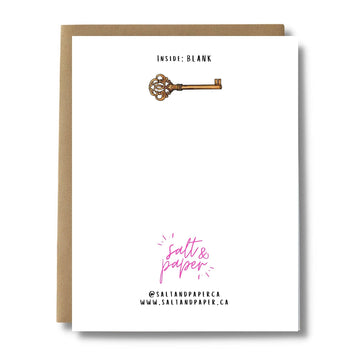 Keys New Home Card - White greeting card with a gold antique-style key illustration and minimal black text, paired with a brown kraft envelope.
