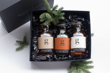 Syrup Gift Box | Gourmet Inspirations - Gift box with three handmade Canadian syrup bottles in a sleek black container, accented with pine sprigs.