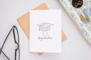 Congraduation Card - Handmade Canadian graduation card with cap illustration and "Congraduation" text on white background, includes kraft envelope.