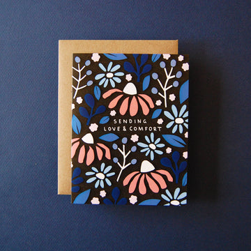 Love & Comfort Everyday Greeting Card - Black greeting card with pink and blue floral design and gold text "Sending Love & Comfort" with a brown kraft envelope.