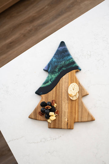 Christmas Tree Resin Charcuterie Board - Christmas tree-shaped charcuterie board with natural wood and blue-green resin top section, holding cheese and nuts.