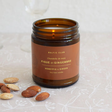 Honey Fig & Ginger Soy Candle - Amber glass jar candle with a warm brown label featuring gold text, surrounded by almonds and hazelnuts on a white floral.