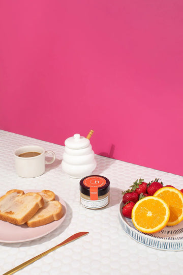 Orange Grove Honey (Chandler Honey) - Jar of Chandler Honey Orange Grove honey with toast, coffee cup, and fresh citrus on pink background, unique Canadian gift.