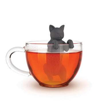 PurrTea Tea Infuser - Black cat-shaped tea infuser made of silicone, hanging over clear glass cup filled with amber tea.