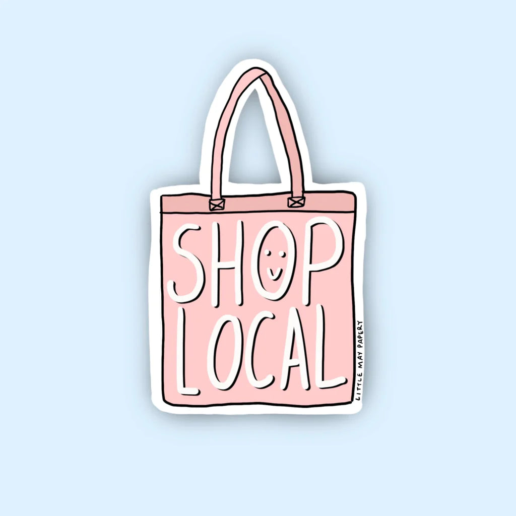 A sticker of a pink tote bag that says "Shop local" with the 'o' in shop as a smiley face