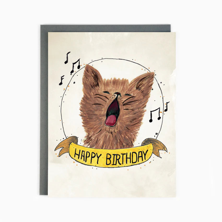 A white card with a brown singing cat and musical notes surrounding it and the words "Happy Birthday"